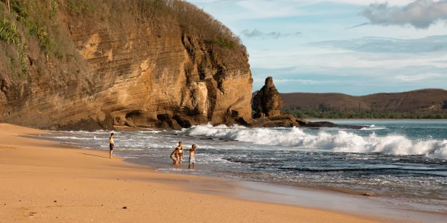 Plage de la Baie Des Tortues ainsi que ses vagues avec une famille qui joue au loin