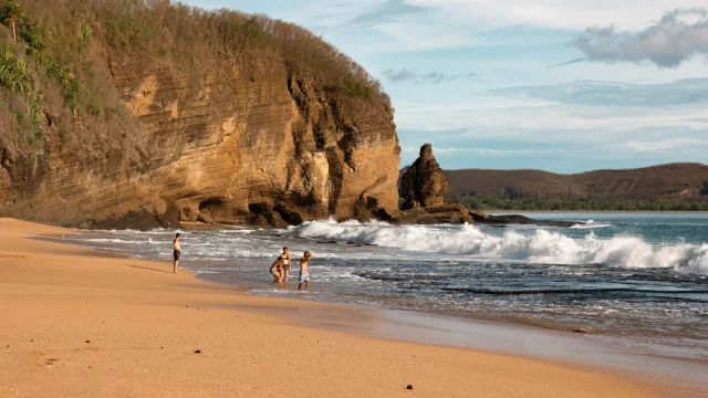 Plage de la Baie Des Tortues ainsi que ses vagues avec une famille qui joue au loin