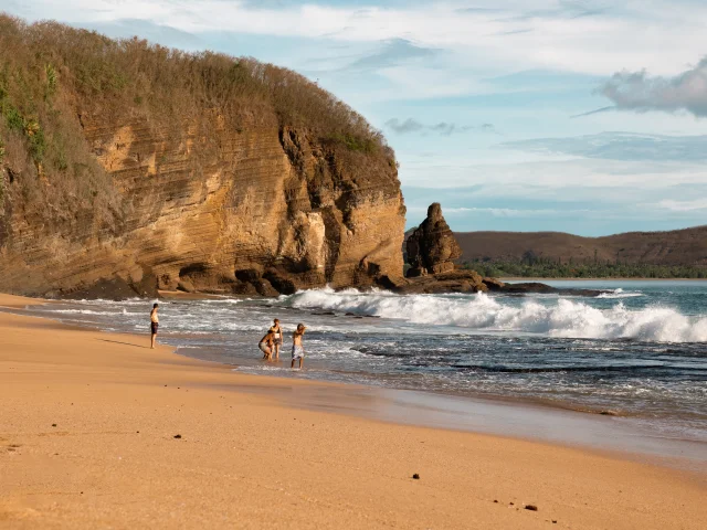 Plage de la Baie Des Tortues ainsi que ses vagues avec une famille qui joue au loin