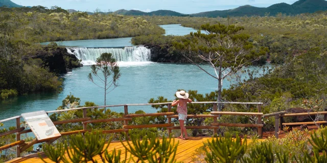 Shot aérien d'une femme qui regarde une cascade dans le Grand Sud de la Nouvelle-Calédonie