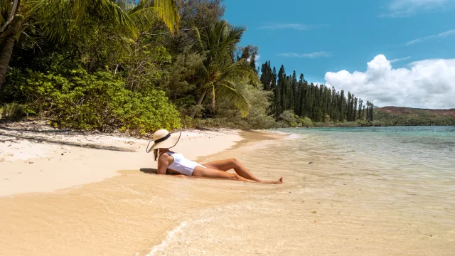 Femme allongée au bord de la plage, les pieds dans l'eau