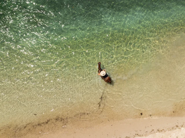 Shot aérien d'une femme à dos de cheval, dans la mer