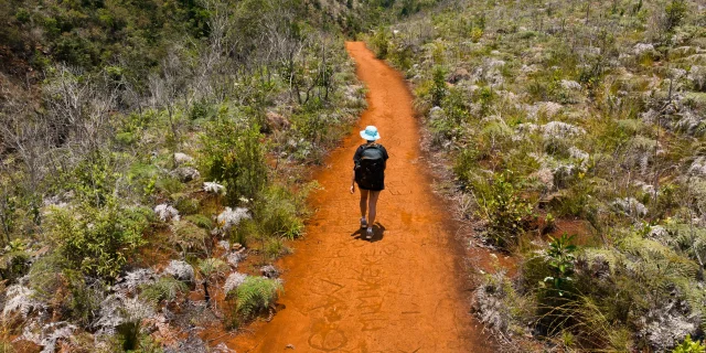 Shot aérien de quelqu'un qui marche sur un chemin en foulant la terre rouge dans le Grand Sud de la Nouvelle-Calédonie